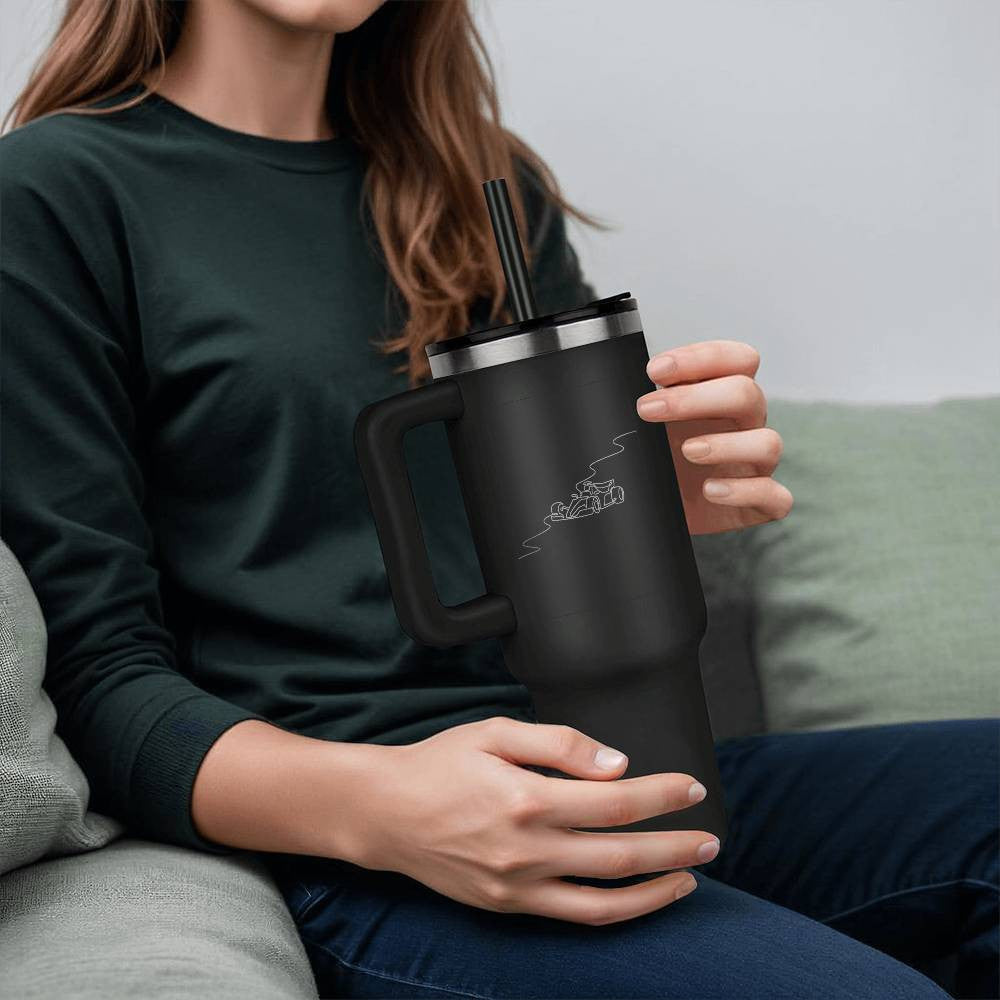Person holding a black water bottle tumbler featuring fan inspired F1 track and race car 