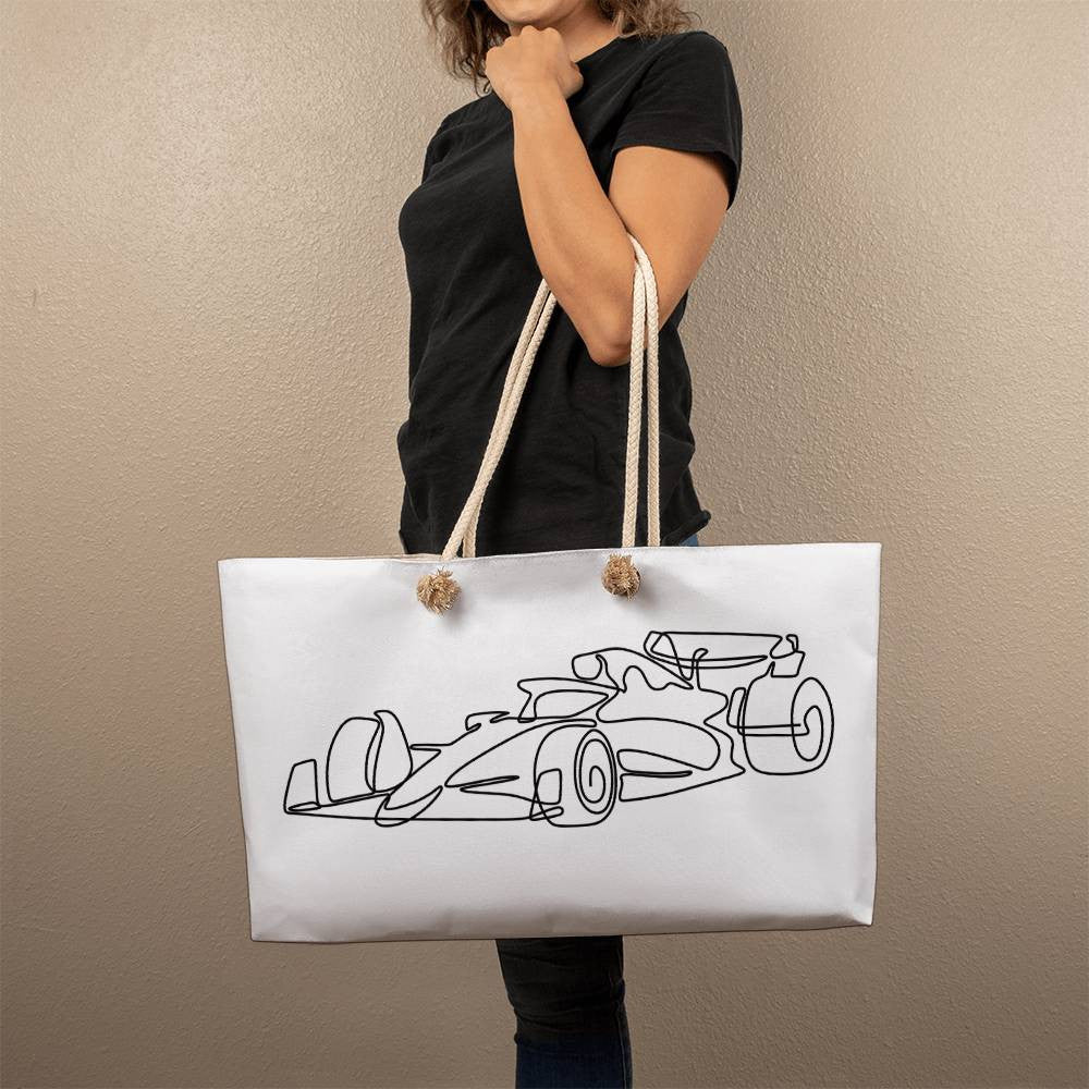 Person holding white F1 tote merch for scale
