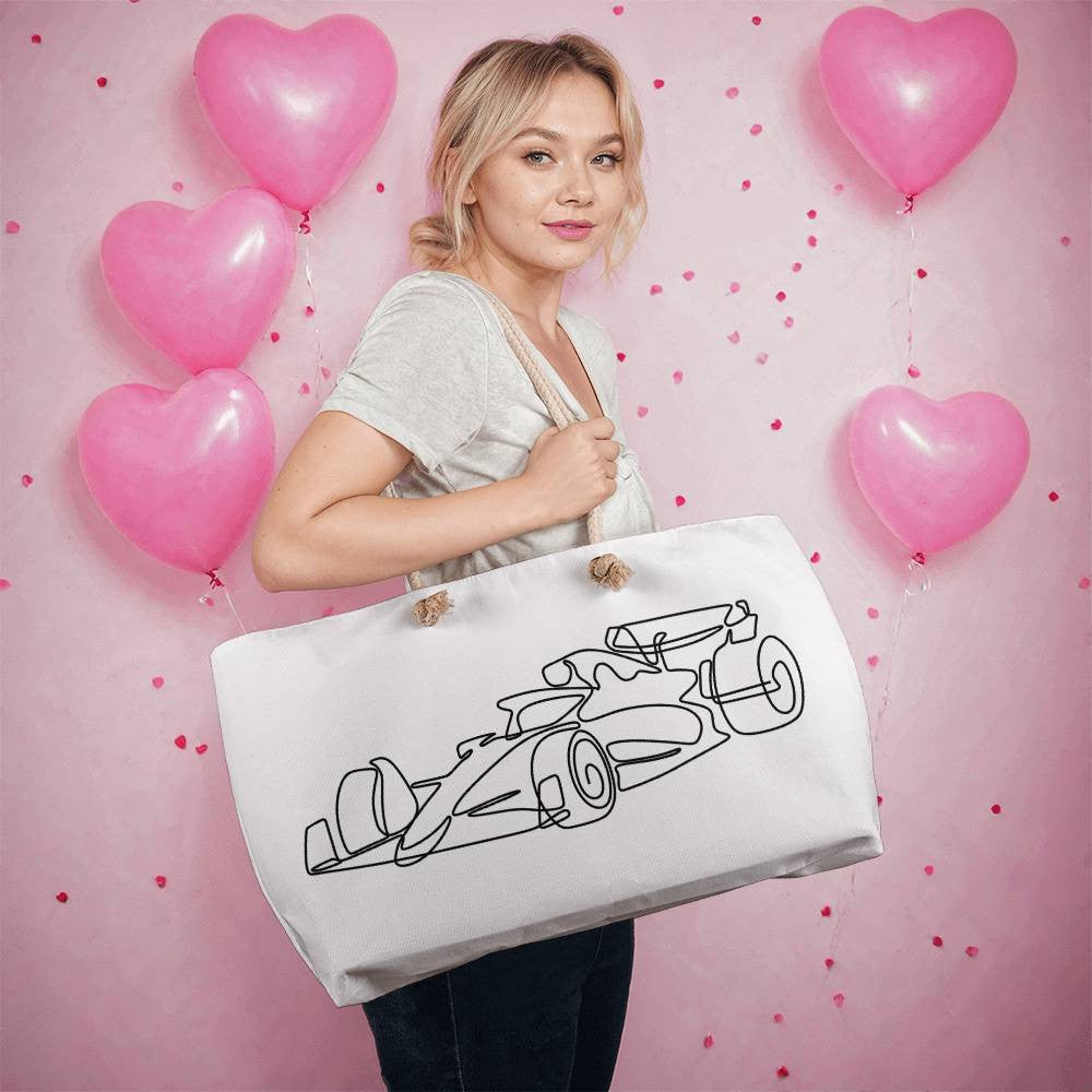 Person holding white tote bag with cloth straps featuring an illustrated black F1 race car