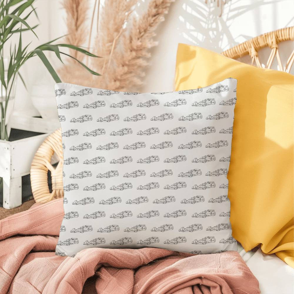 White formula one pillow with black cars sitting on a chair with a blanket