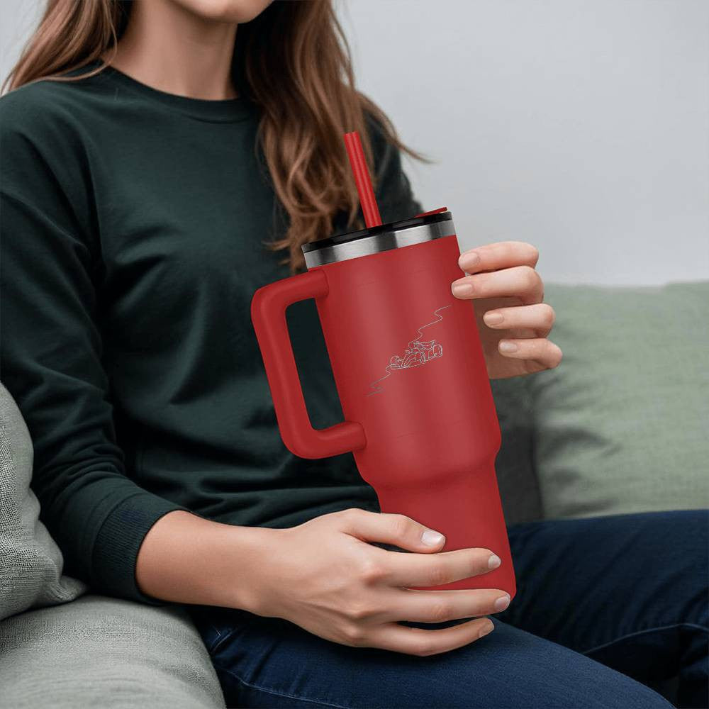 person holding red water bottle tumbler with a straw featuring an illustrated F1 track and race car